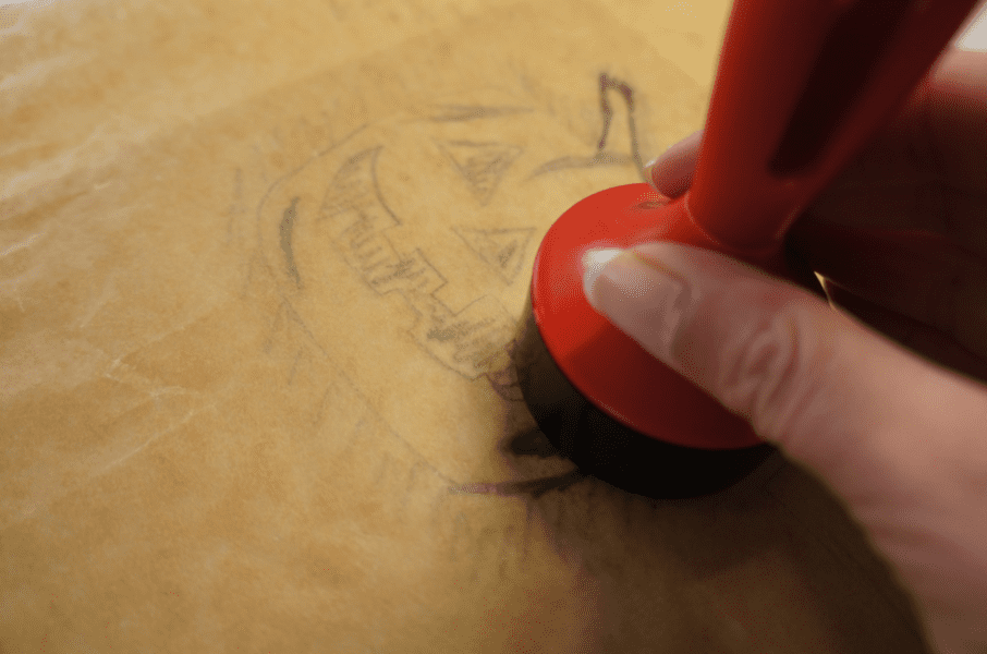 a red Essdee baren being used to rub the pumpkin design from the tracing paper onto the SoftCut