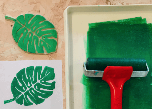 ink tray with green ink, roller, and piece of lino cut into a monserta leaf