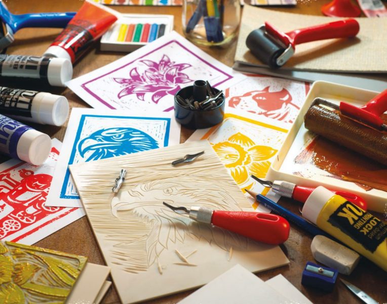 selection of inks, softcut, and carving materials laid out on a table