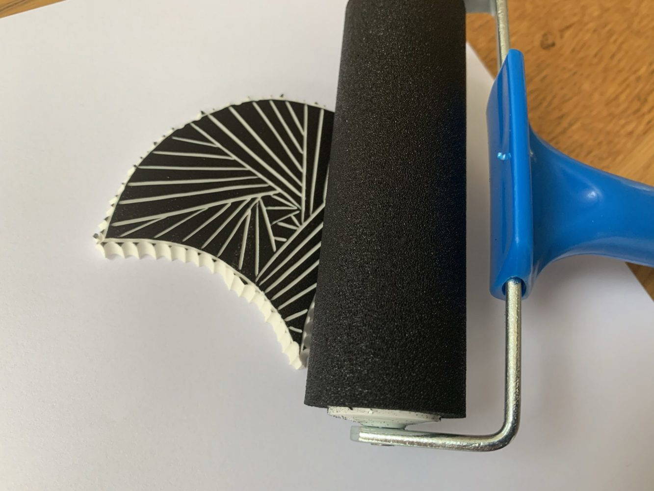 Black fabric ink being transferred onto fan design using a fabric roller