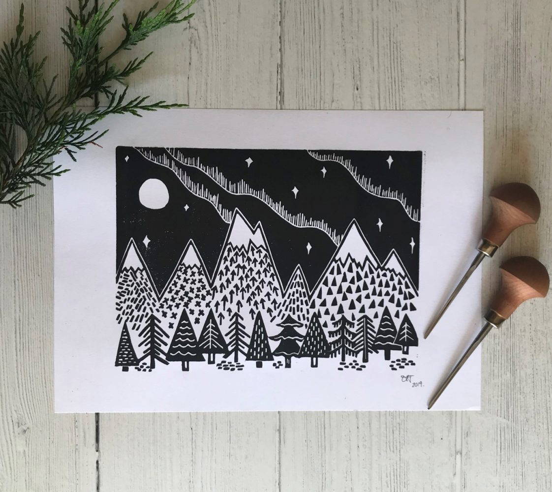 Linoprint of mountains and trees in black and white