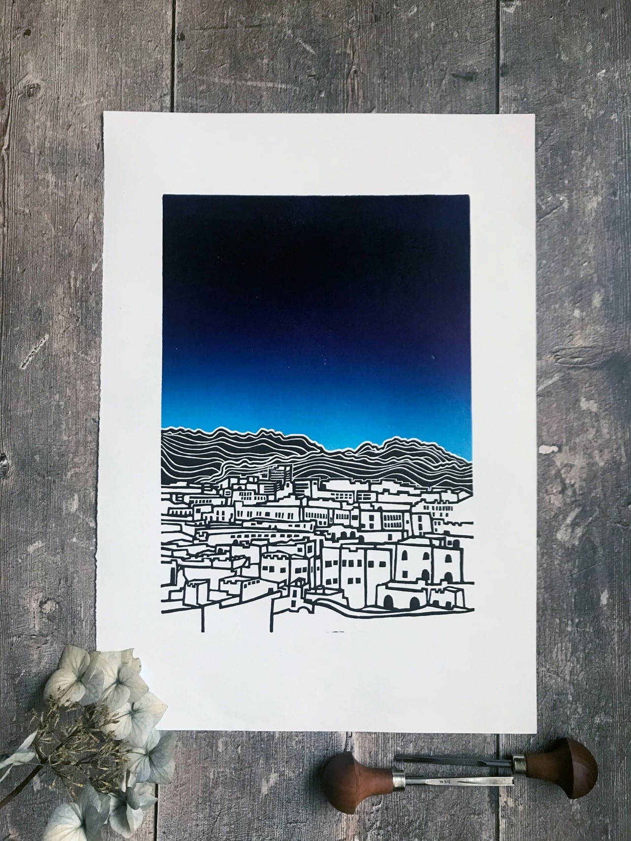 Lino print of city with a brilliant blue sky