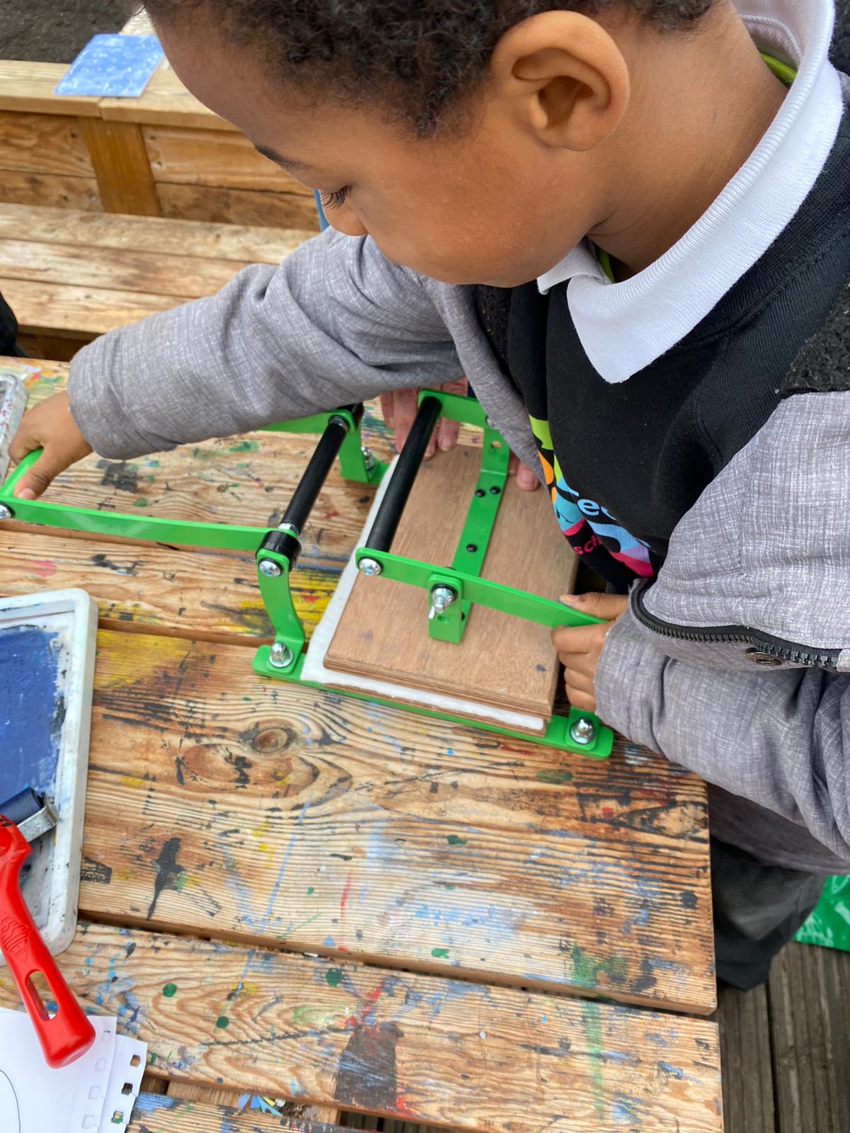 Children learning to linoprint using a press