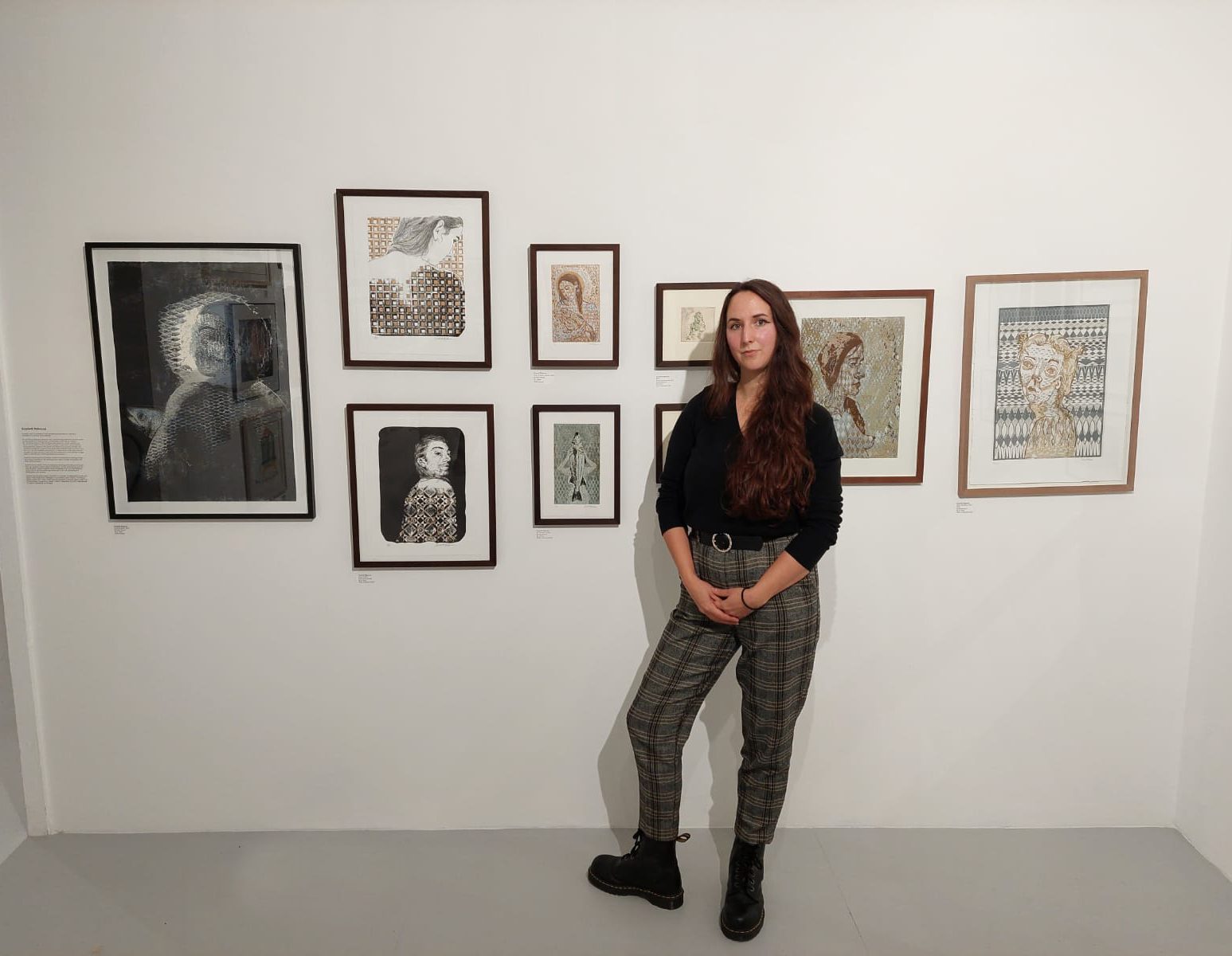 Photo of printmaker Scarlett Rebecca in front of a gallery display of her prints